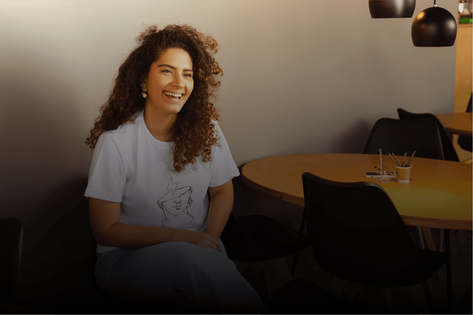 A smiling team member sitting at a table in a bright office